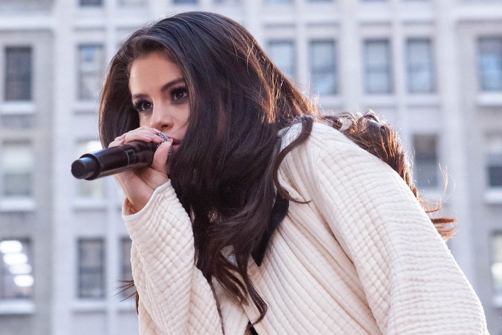 Selena Gomez cantando sobre el escenario con un micrófono